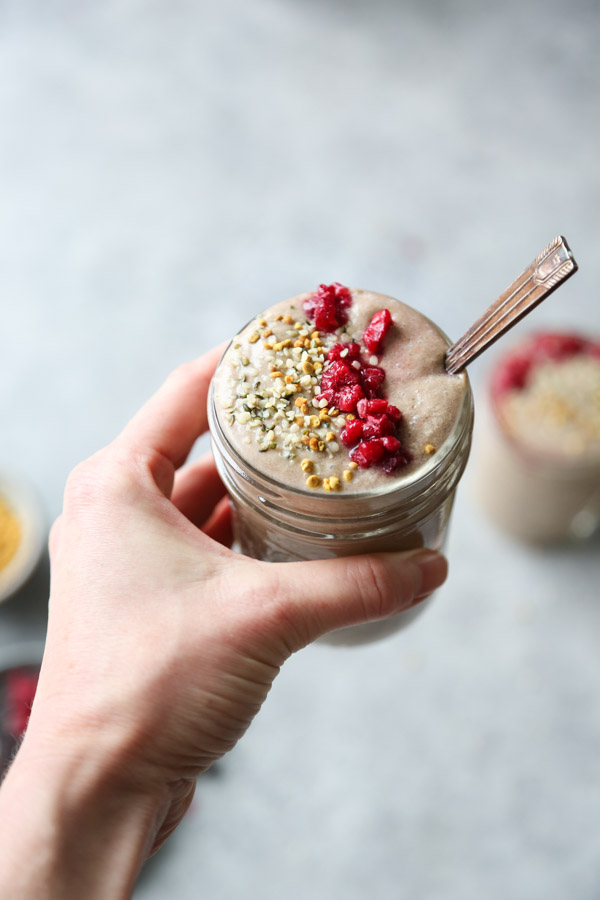 raspberry smoothie with bee pollen and hibiscus in a glass with hand